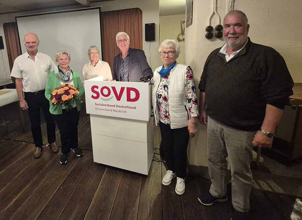 Gruppenbild mit mehreren Personen hinter einem SoVD-Pult. 