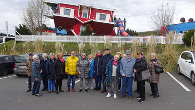 Reisegruppe vor auf dem Kopf stehenden Haus