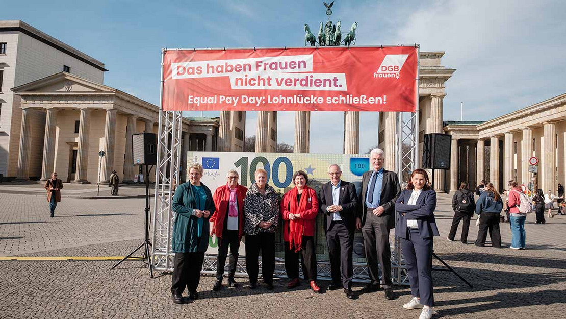 Acht Personen vor dem Brandenburger Tor in Berlin. Hinter ihnen ein Transparent mit der Aufschrift "Das haben Frauen nicht verdient". 