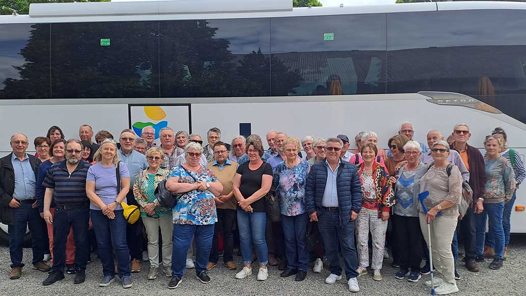 Große Menschengruppe steht vor einem Reisebus.