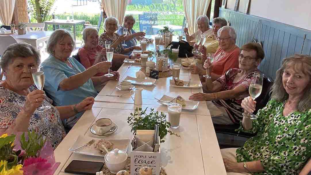 Langer Tisch mit vielen Frauen, die ein Glas Sekt hochhalten.